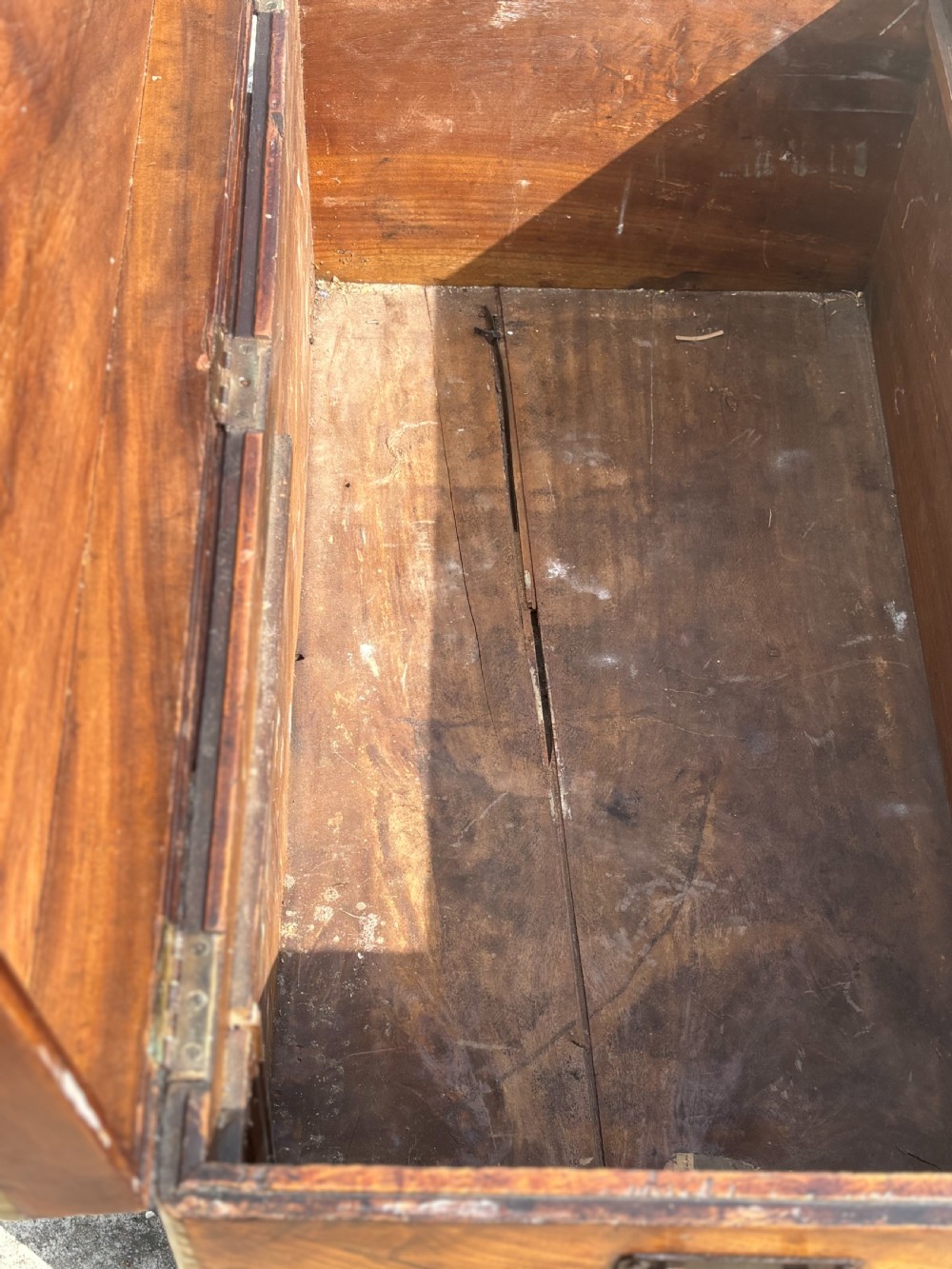 A rectangular 19th-century camphor wood campaign trunk with brass corner strapping, edge binding, a central flush plaque, and iron side handles. View XII
