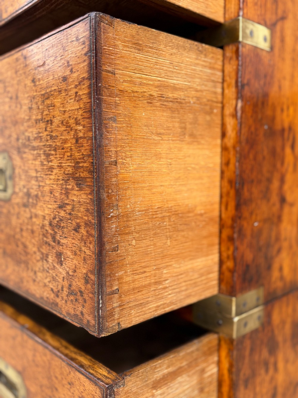 A nineteenth-century oak military campaign chest of drawers featuring brass corner straps, recessed flush handles, and turned feet. View XVI