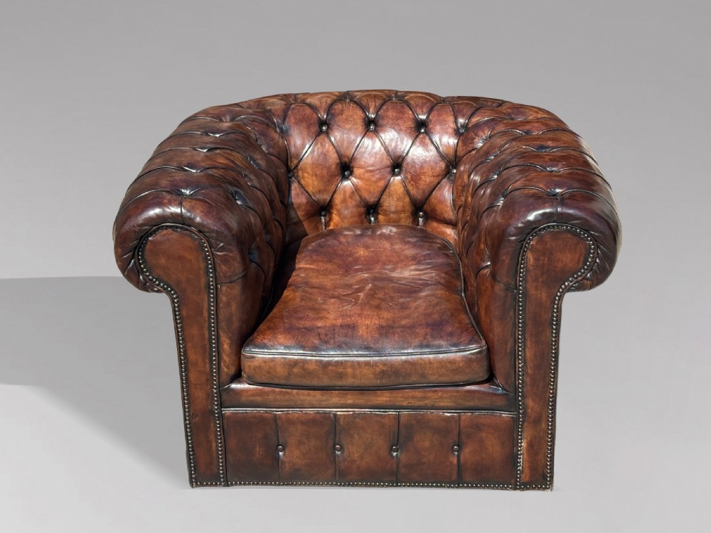 An Edwardian brown leather Chesterfield armchair featuring deep button quilting, rolled arms, and stud trim details. View III
