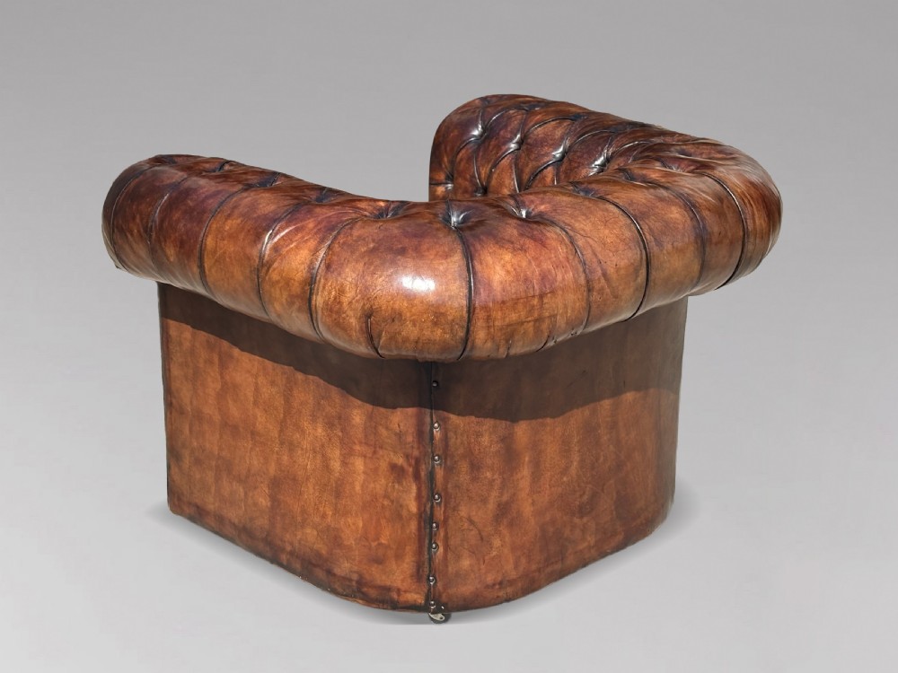 An Edwardian brown leather Chesterfield armchair featuring deep button quilting, rolled arms, and stud trim details. View VII
