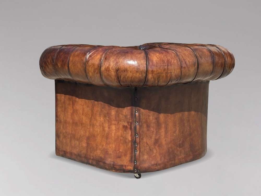 An Edwardian brown leather Chesterfield armchair featuring deep button quilting, rolled arms, and stud trim details. View IX