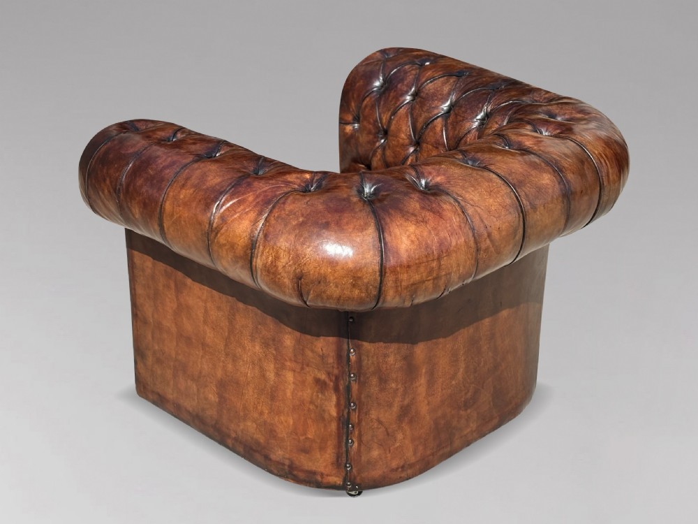 An Edwardian brown leather Chesterfield armchair featuring deep button quilting, rolled arms, and stud trim details. View XI