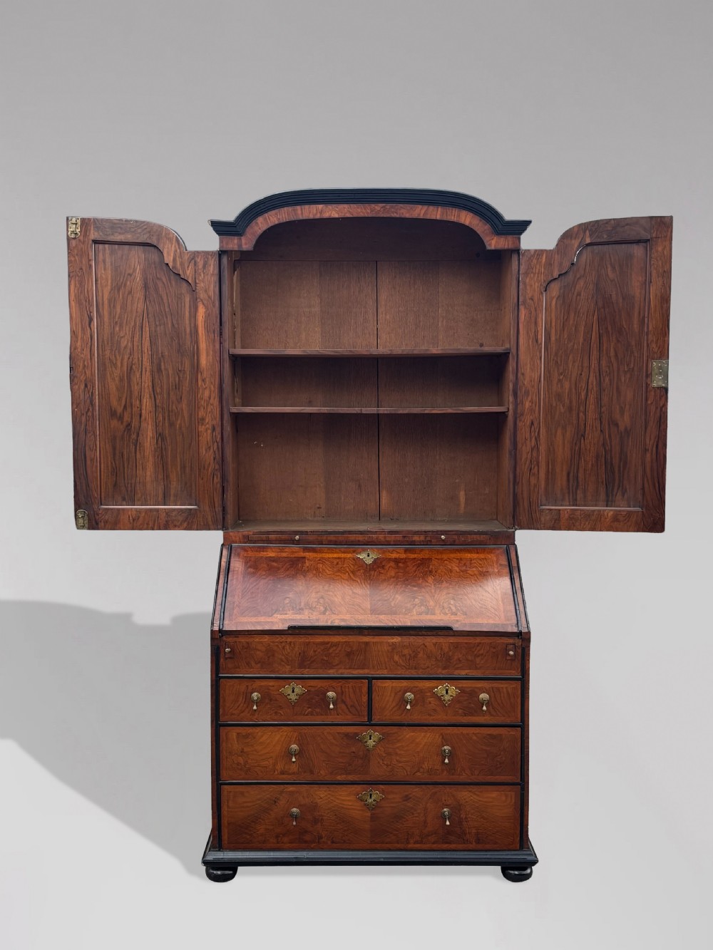 An 18th-century George I walnut bureau bookcase featuring arched panelled upper doors, a slant-front desk, and graduated lower drawers. View X
