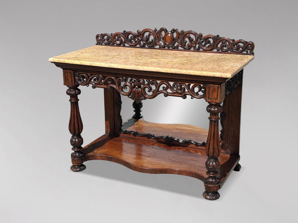 A 19th-century carved rosewood console table featuring a light marble top, elaborate pierced scrollwork frieze, mirrored back panel, and a shaped lower shelf.