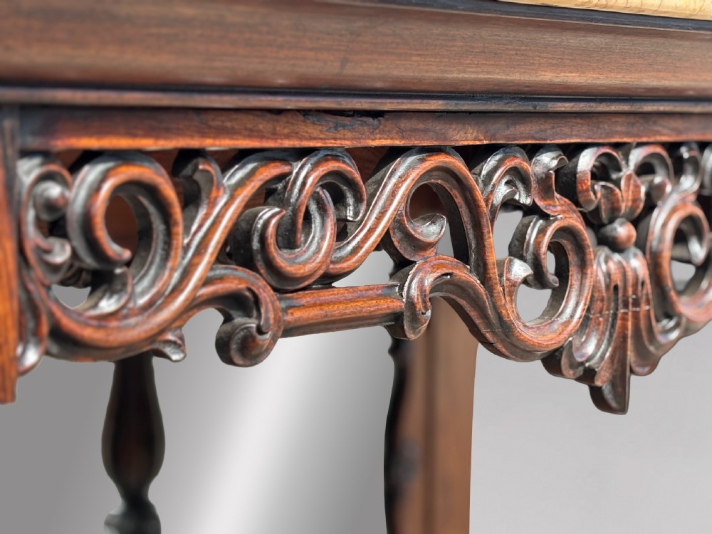 A 19th-century carved rosewood console table featuring a light marble top, elaborate pierced scrollwork frieze, mirrored back panel, and a shaped lower shelf. View VI
