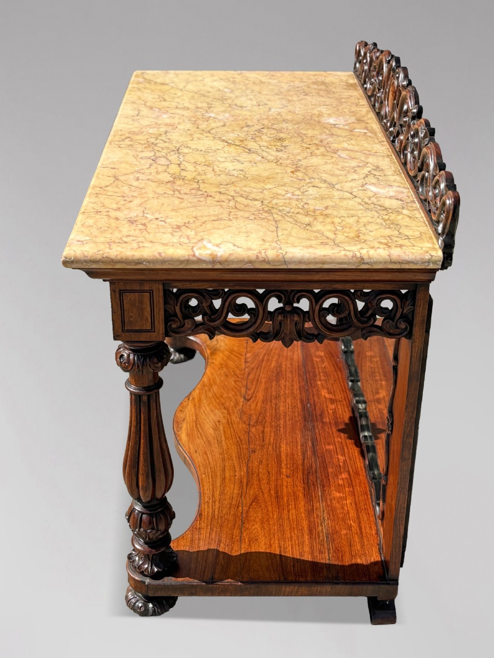 A 19th-century carved rosewood console table featuring a light marble top, elaborate pierced scrollwork frieze, mirrored back panel, and a shaped lower shelf. View VII