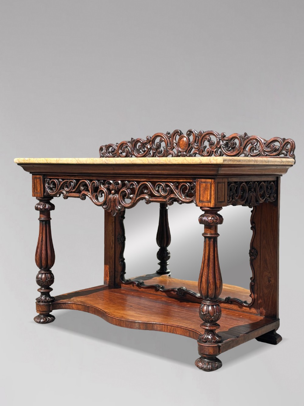 A 19th-century carved rosewood console table featuring a light marble top, elaborate pierced scrollwork frieze, mirrored back panel, and a shaped lower shelf. View XV