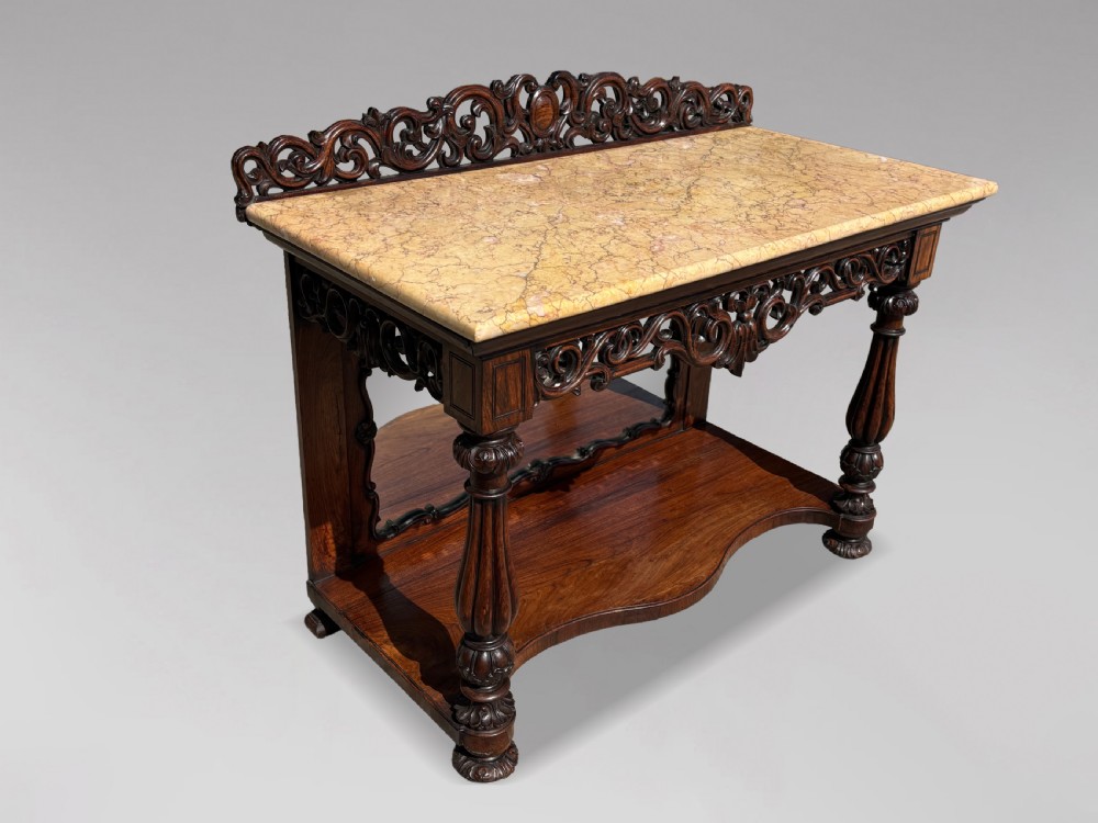 A 19th-century carved rosewood console table featuring a light marble top, elaborate pierced scrollwork frieze, mirrored back panel, and a shaped lower shelf. View XVI
