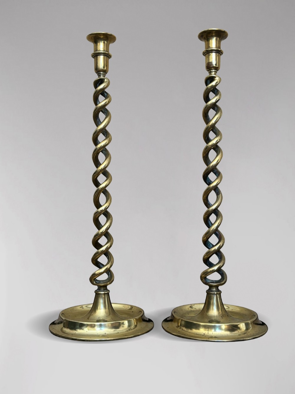 A pair of tall Victorian brass candlesticks featuring open barley twist stems and circular stepped bases.