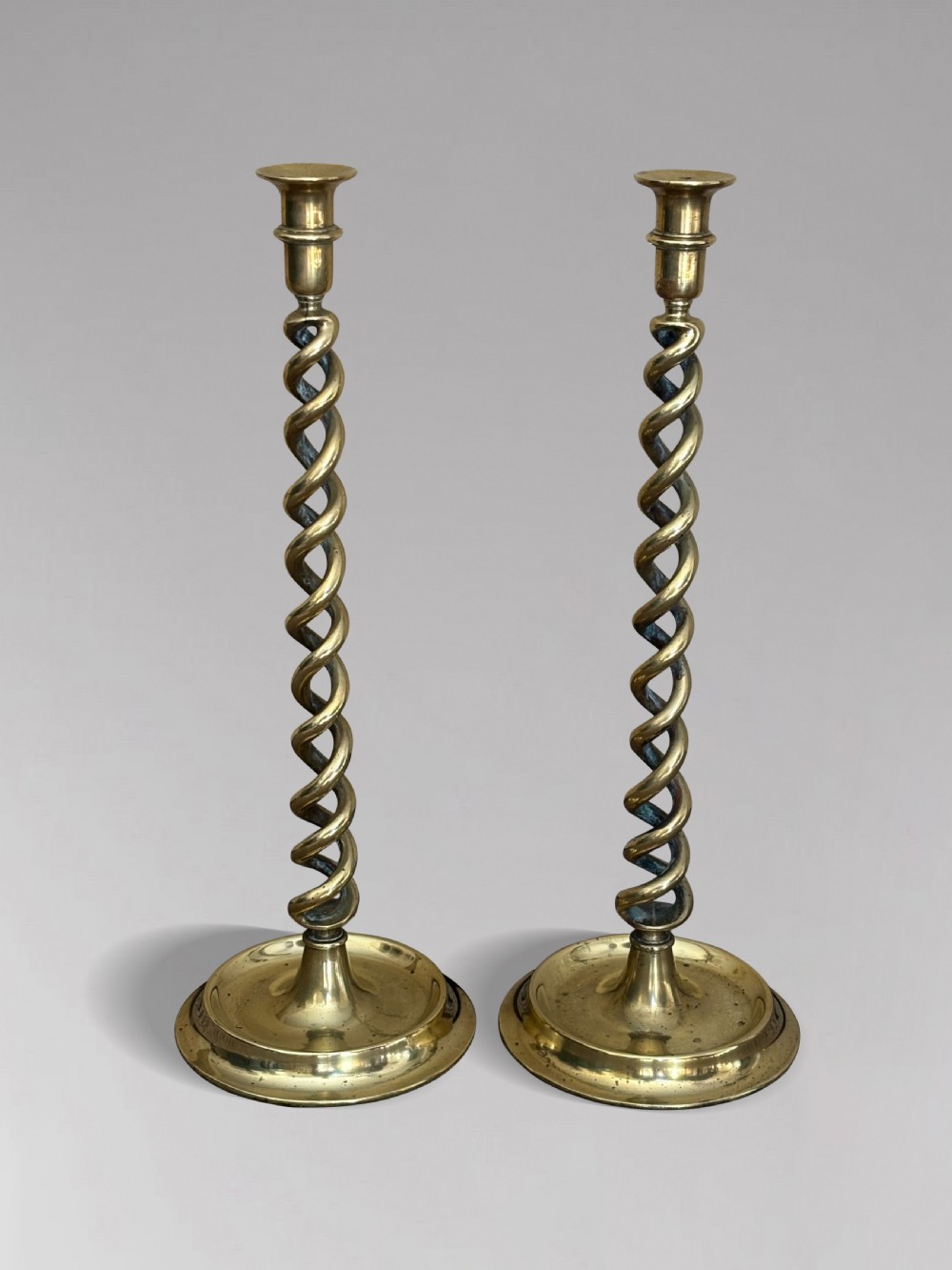A pair of tall Victorian brass candlesticks featuring open barley twist stems and circular stepped bases. View IV