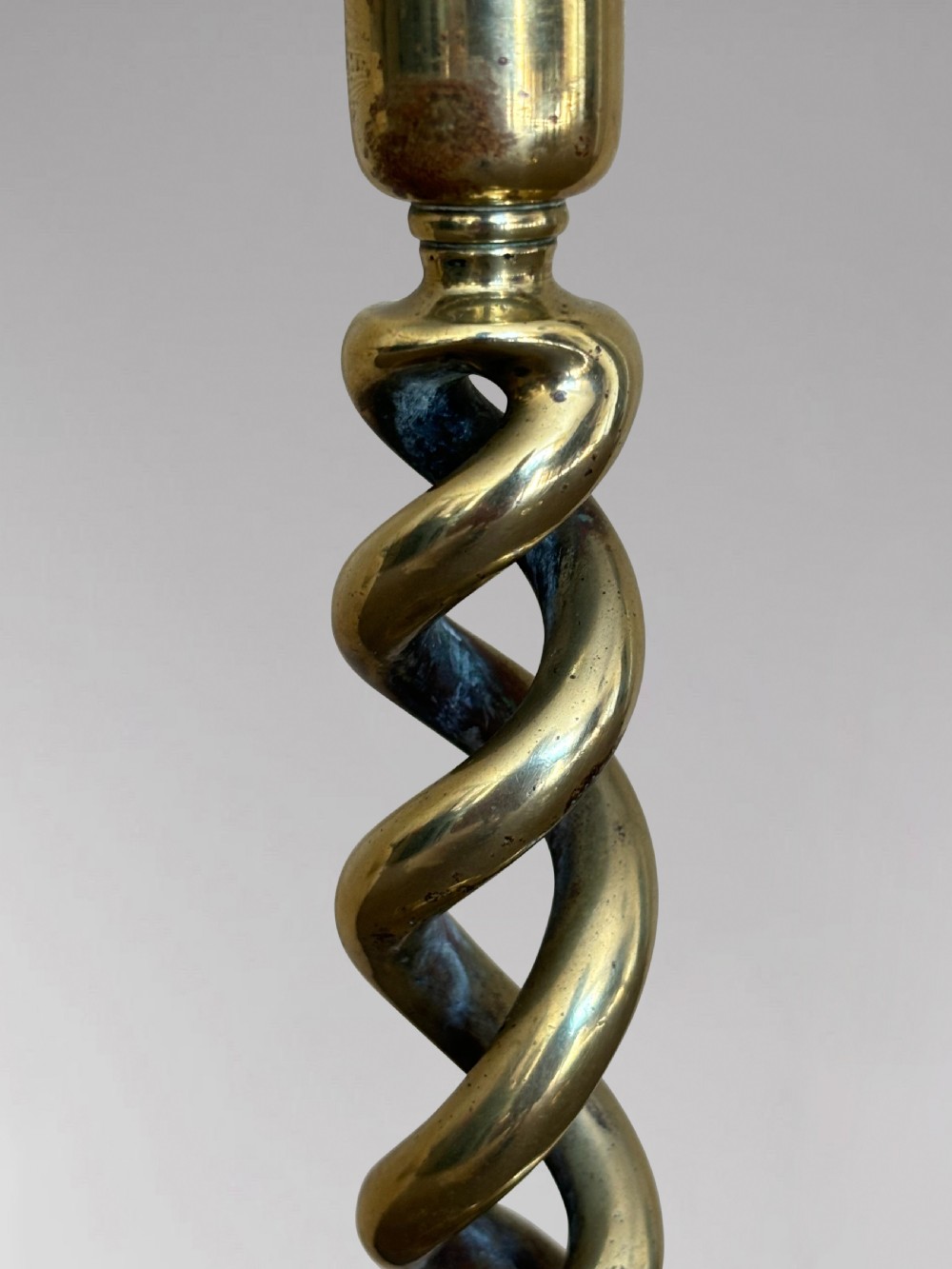 A pair of tall Victorian brass candlesticks featuring open barley twist stems and circular stepped bases. View V