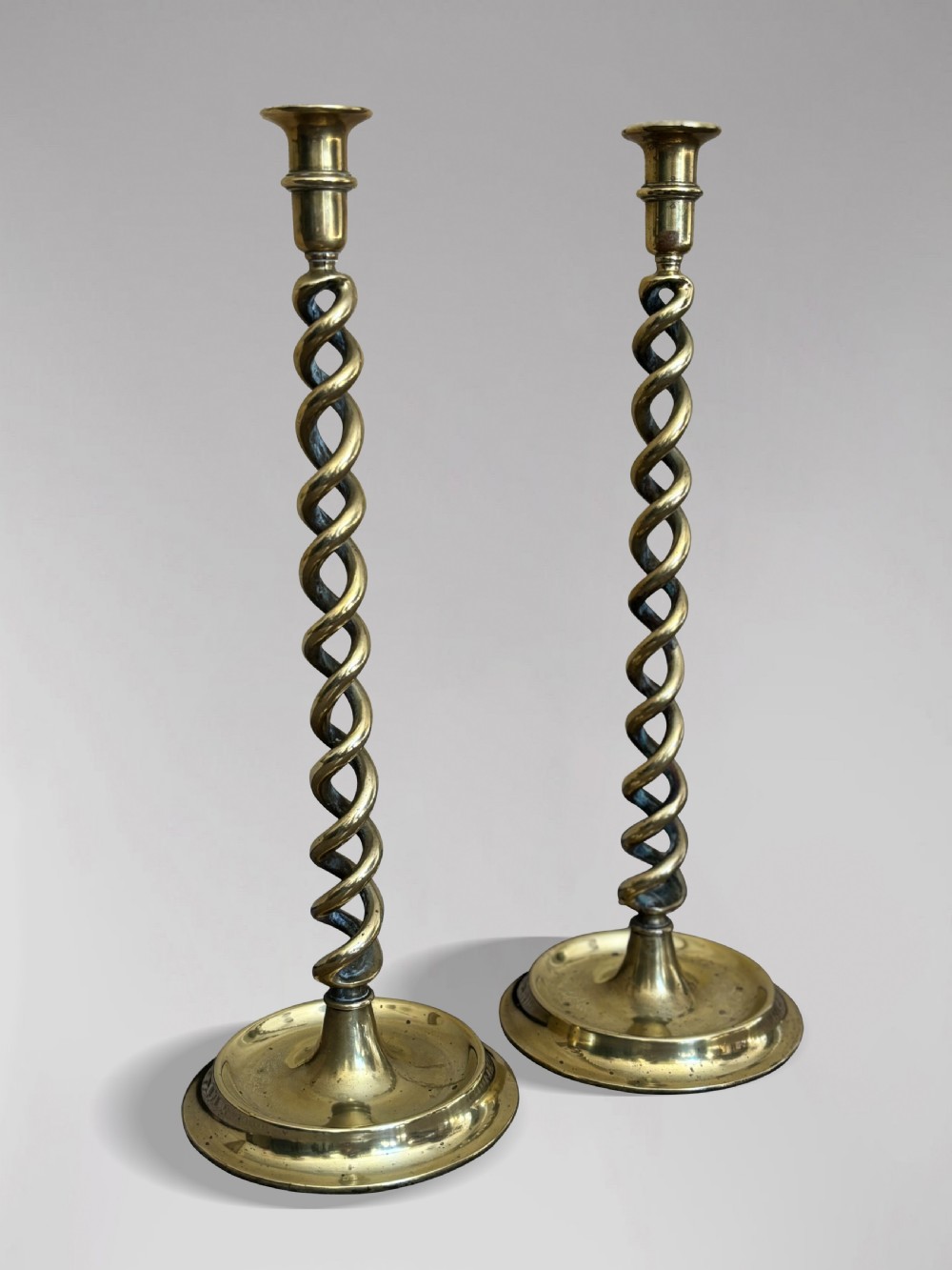 A pair of tall Victorian brass candlesticks featuring open barley twist stems and circular stepped bases. View VI
