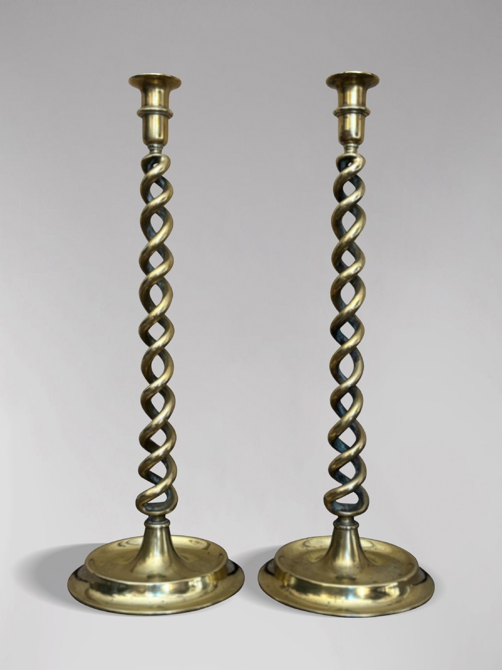 A pair of tall Victorian brass candlesticks featuring open barley twist stems and circular stepped bases. View VII