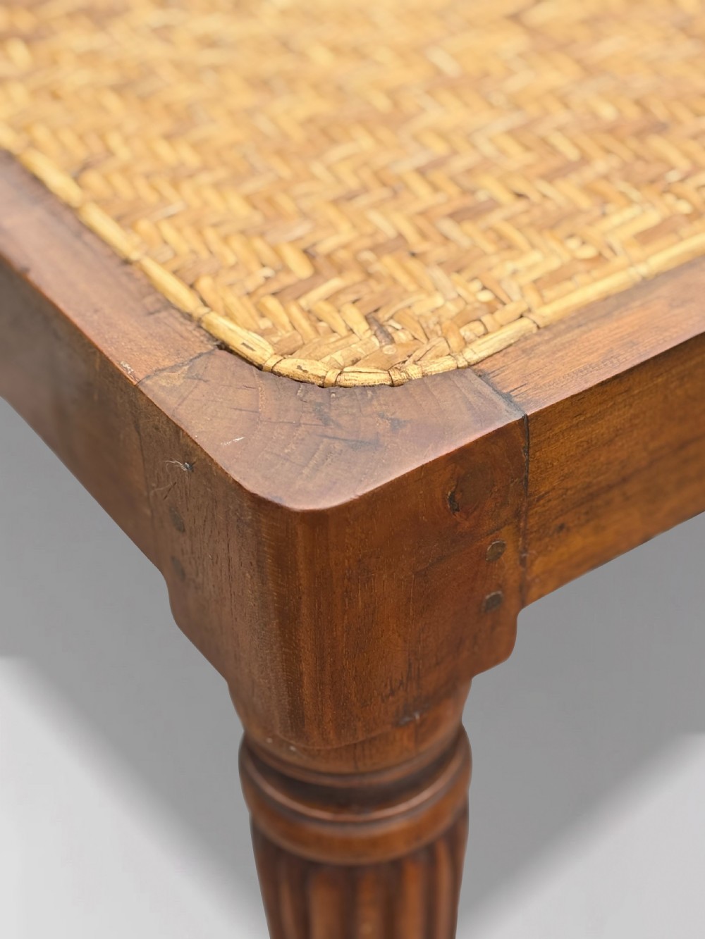 A 19th-century rectangular teak stool with fluted turned legs and a cream textured upholstered cushion top. View IV