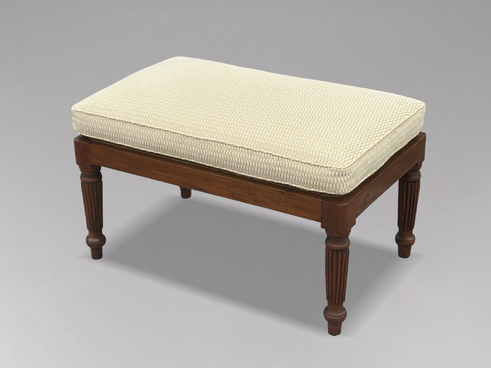 A 19th-century rectangular teak stool with fluted turned legs and a cream textured upholstered cushion top. View X