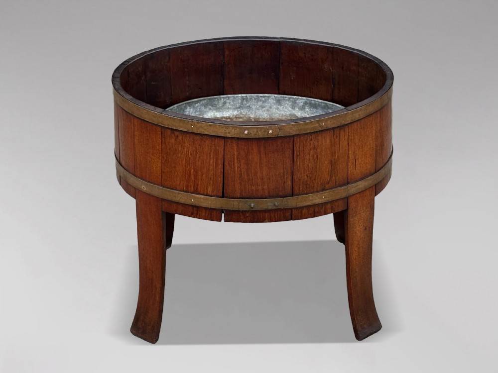 An 18th-century George III oval staved walnut wine cooler featuring twin brass binding bands, splayed legs, and an internal metal liner. View II