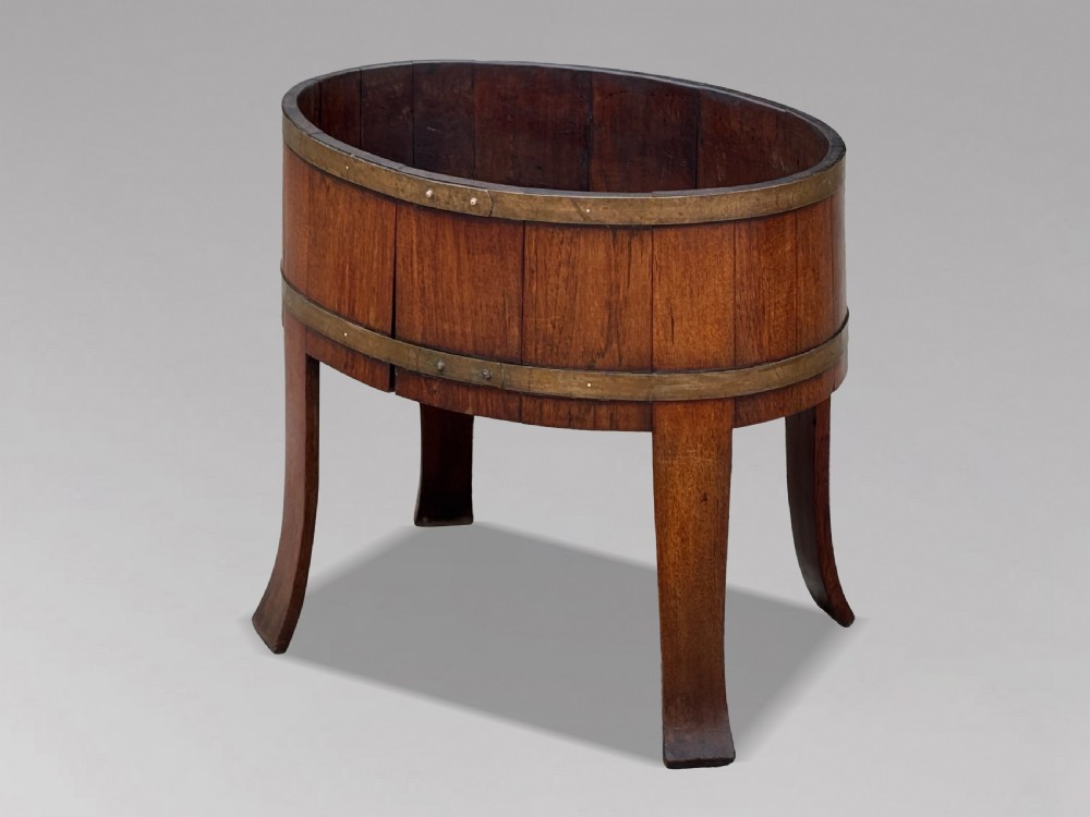 An 18th-century George III oval staved walnut wine cooler featuring twin brass binding bands, splayed legs, and an internal metal liner. View III
