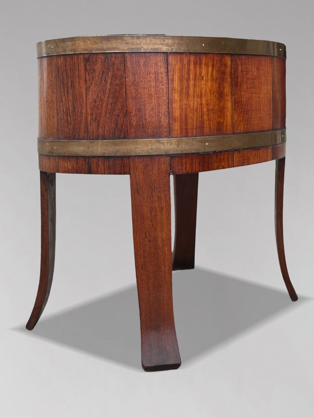 An 18th-century George III oval staved walnut wine cooler featuring twin brass binding bands, splayed legs, and an internal metal liner. View VII