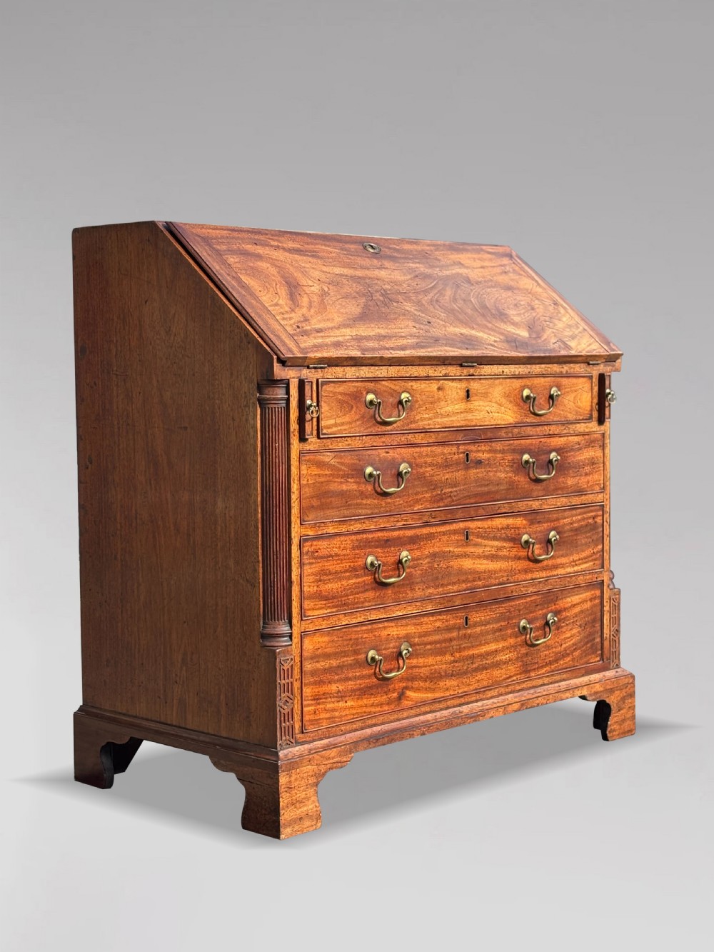 An 18th-century George III mahogany bureau featuring a sloping fall-front writing flap above four graduated drawers with brass handles and bracket feet. View IV