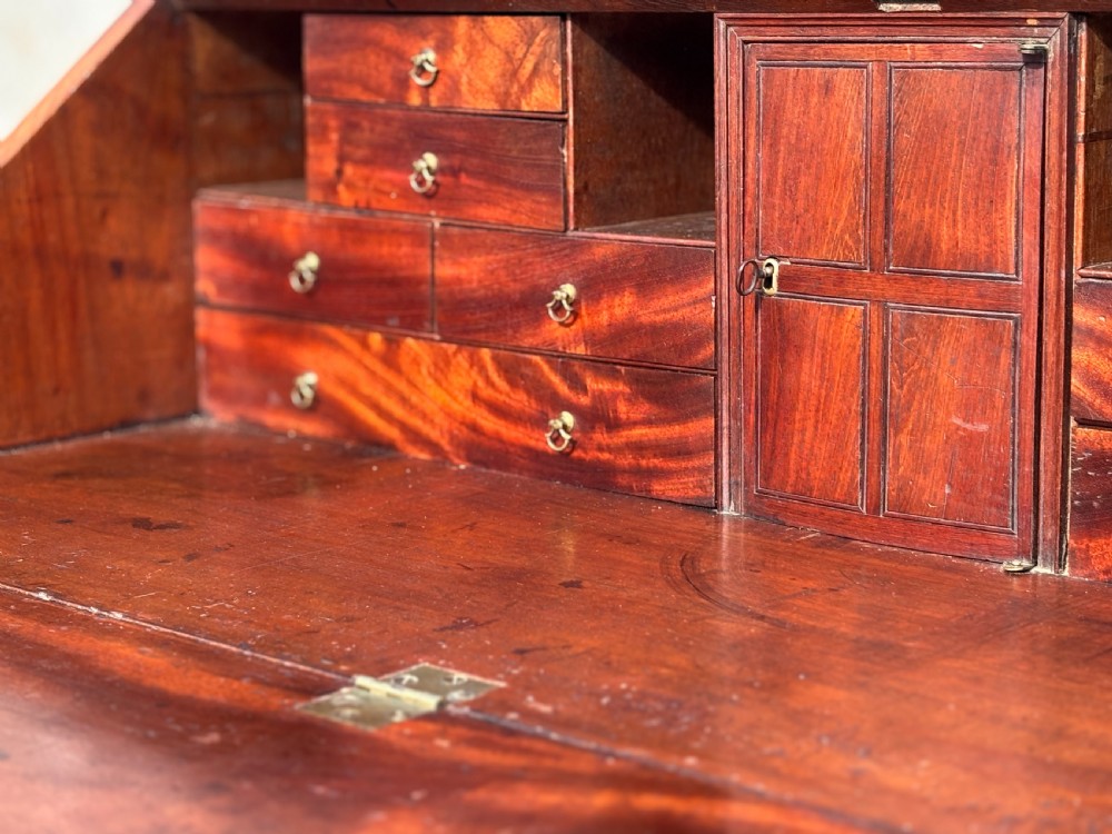 An 18th-century George III mahogany bureau featuring a sloping fall-front writing flap above four graduated drawers with brass handles and bracket feet. View VII