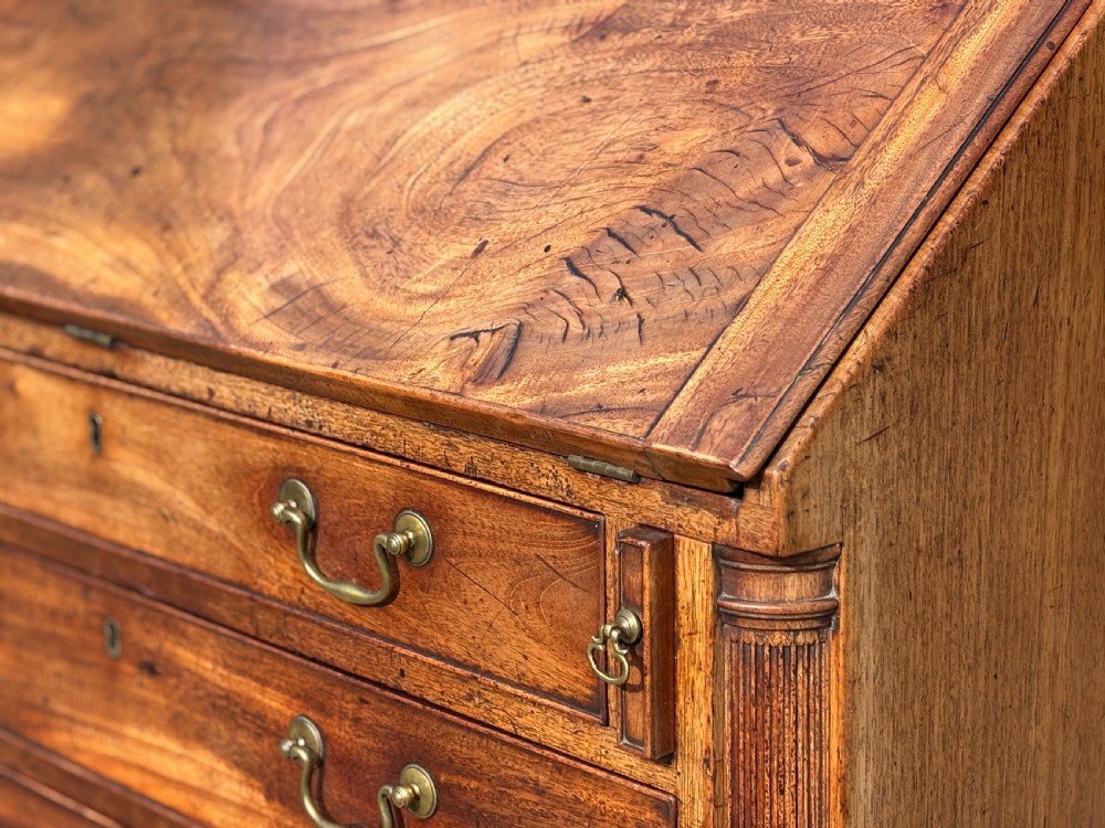 An 18th-century George III mahogany bureau featuring a sloping fall-front writing flap above four graduated drawers with brass handles and bracket feet. View XI