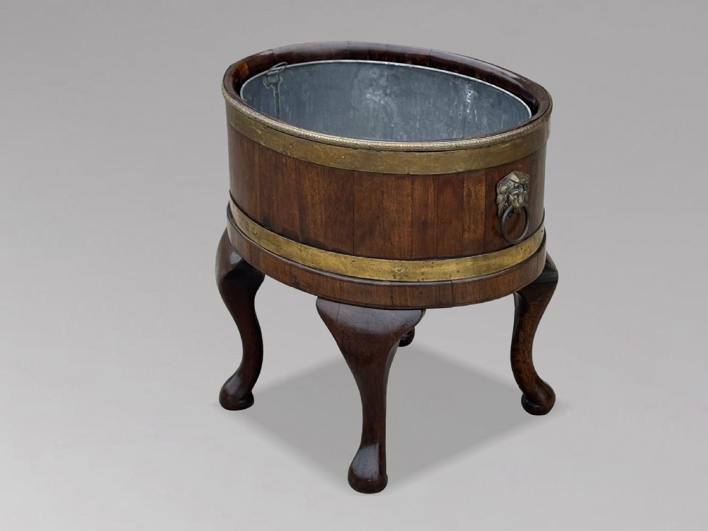 A pair of oval eighteenth-century Georgian mahogany wine coolers featuring brass banding, lion mask drop handles, metal liners, and cabriole legs. View II