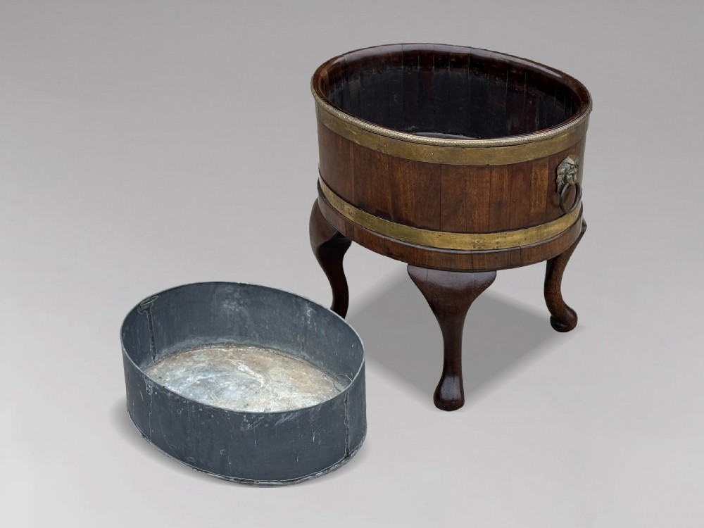 A pair of oval eighteenth-century Georgian mahogany wine coolers featuring brass banding, lion mask drop handles, metal liners, and cabriole legs. View III