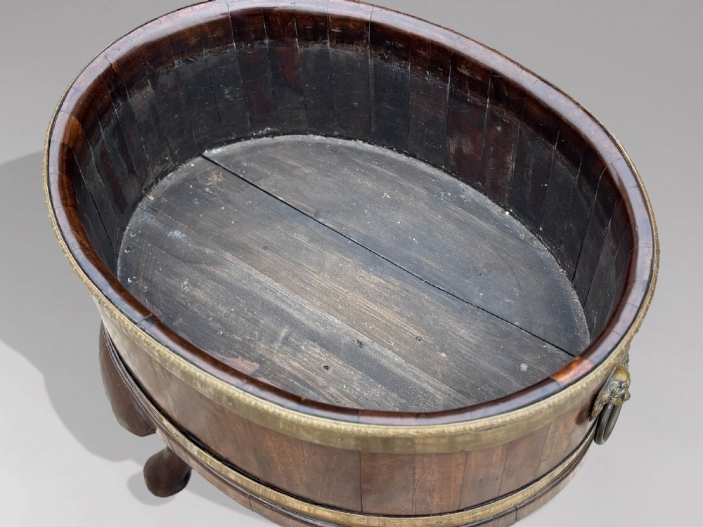 A pair of oval eighteenth-century Georgian mahogany wine coolers featuring brass banding, lion mask drop handles, metal liners, and cabriole legs. View VII