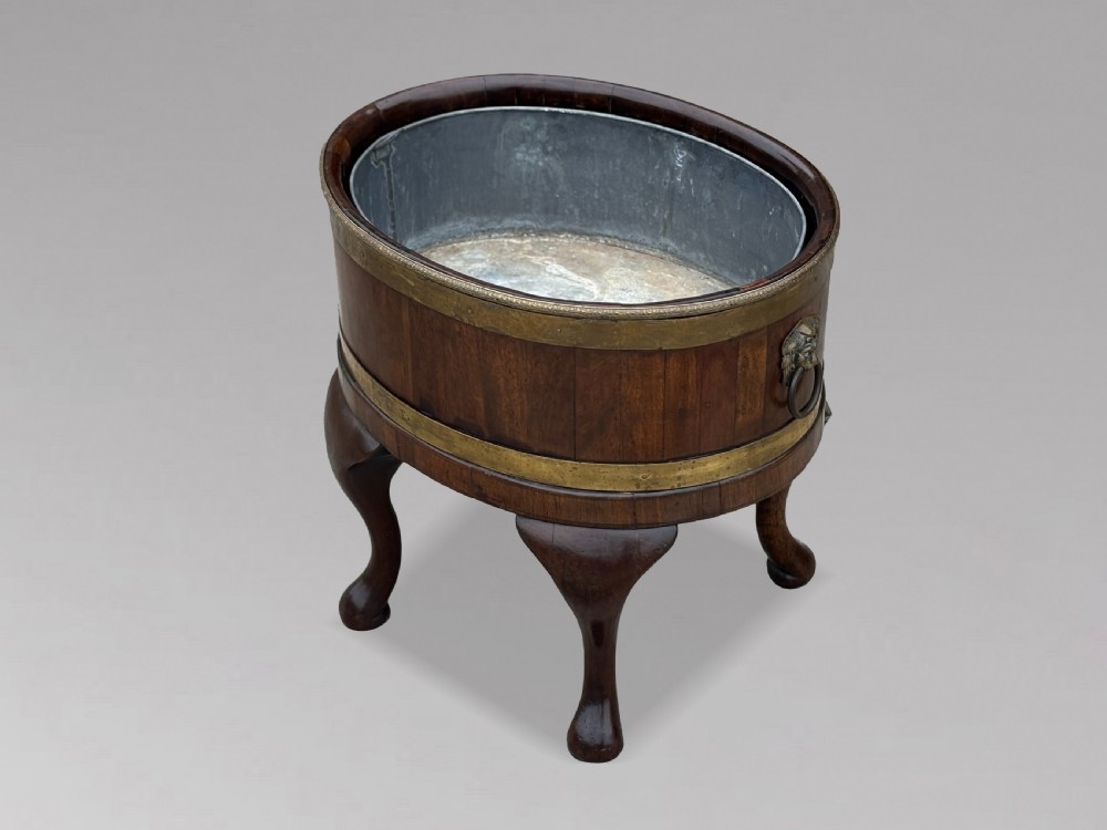 A pair of oval eighteenth-century Georgian mahogany wine coolers featuring brass banding, lion mask drop handles, metal liners, and cabriole legs. View IX
