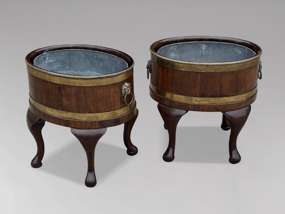 A pair of oval eighteenth-century Georgian mahogany wine coolers featuring brass banding, lion mask drop handles, metal liners, and cabriole legs. View X