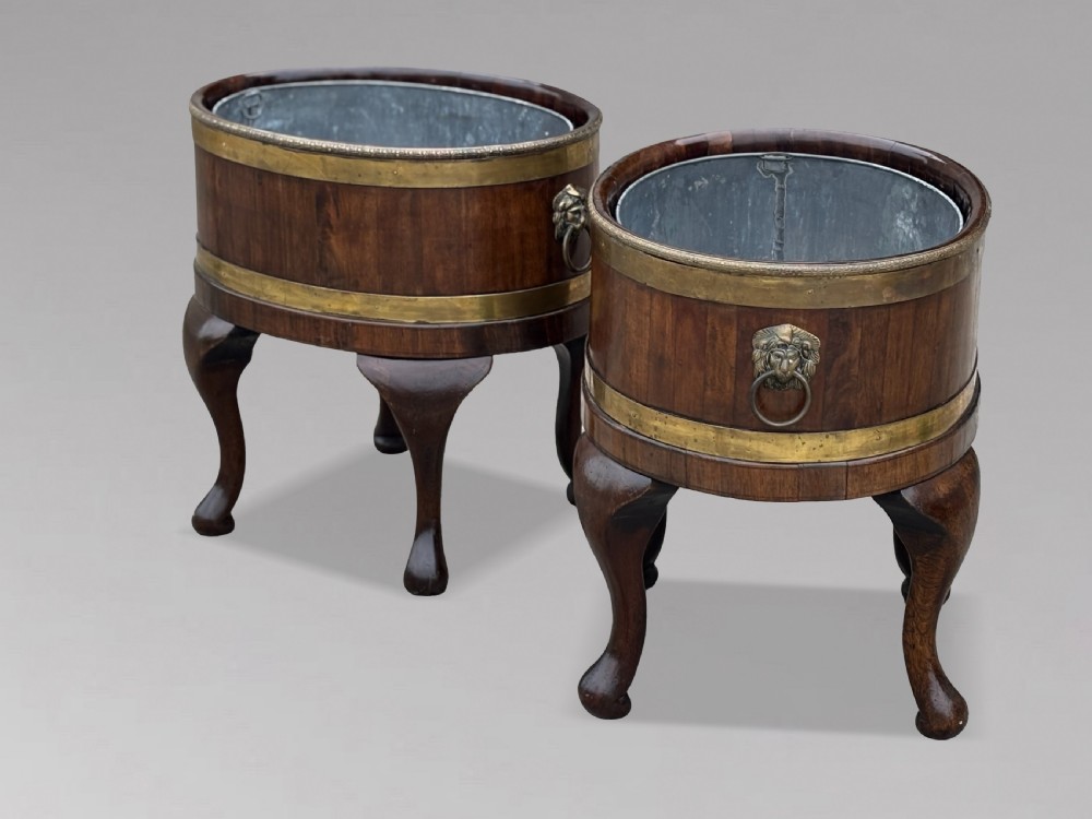 A pair of oval eighteenth-century Georgian mahogany wine coolers featuring brass banding, lion mask drop handles, metal liners, and cabriole legs. View XI