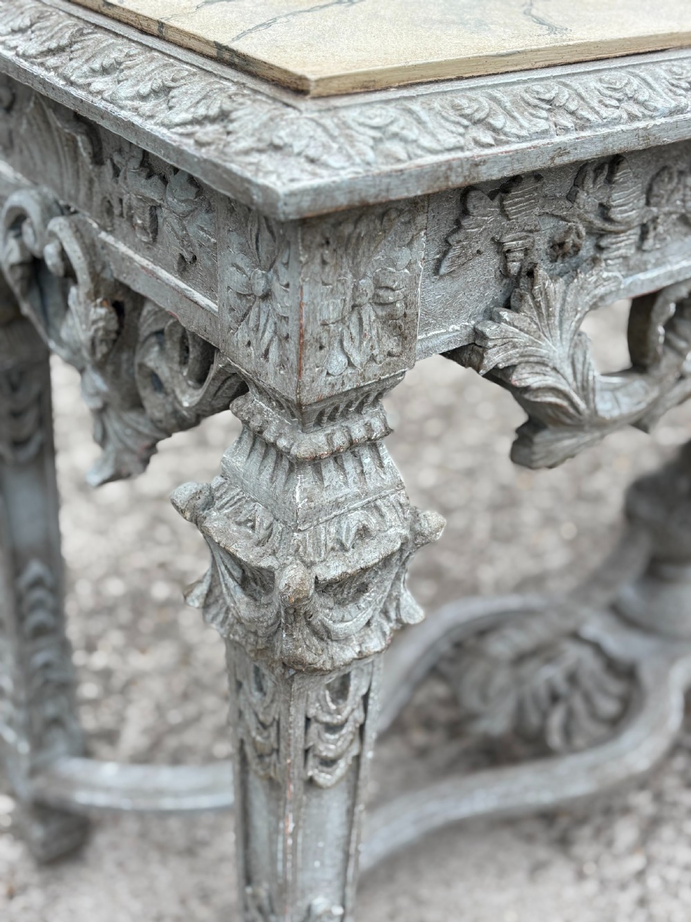 A carved Louis XIV style grey painted console table with an intricate aproned skirt, stretcher base, and faux marble top. View X