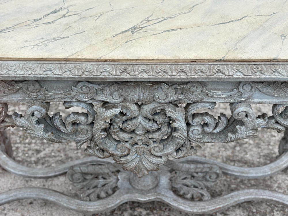 A carved Louis XIV style grey painted console table with an intricate aproned skirt, stretcher base, and faux marble top. View XI
