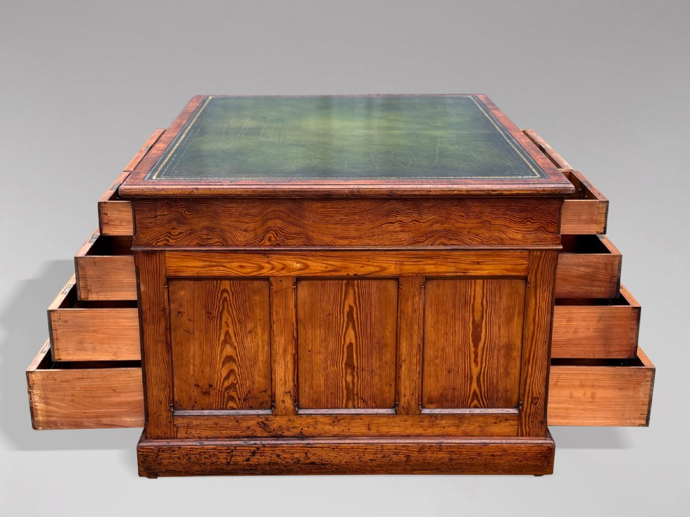 A Victorian pitch pine partners desk featuring a green leather inset writing surface, twin pedestals, and brass swan-neck handles. View II