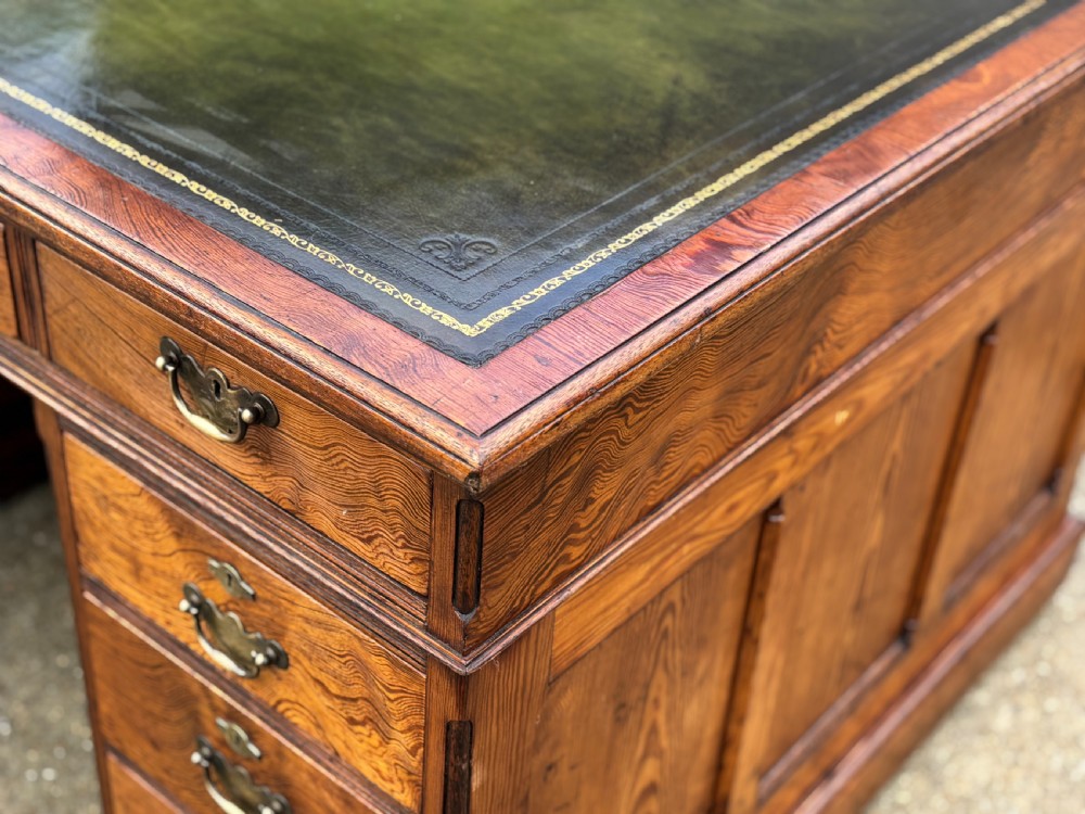 A Victorian pitch pine partners desk featuring a green leather inset writing surface, twin pedestals, and brass swan-neck handles. View IV