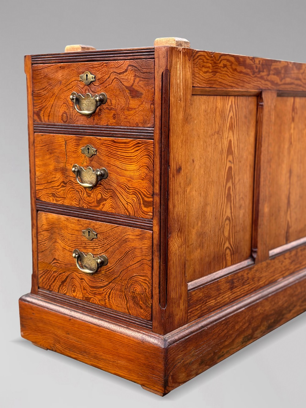 A Victorian pitch pine partners desk featuring a green leather inset writing surface, twin pedestals, and brass swan-neck handles. View VII