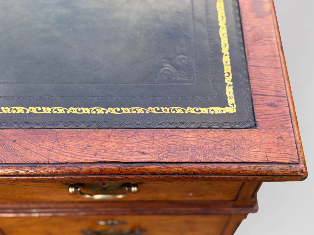 A Victorian pitch pine partners desk featuring a green leather inset writing surface, twin pedestals, and brass swan-neck handles. View X