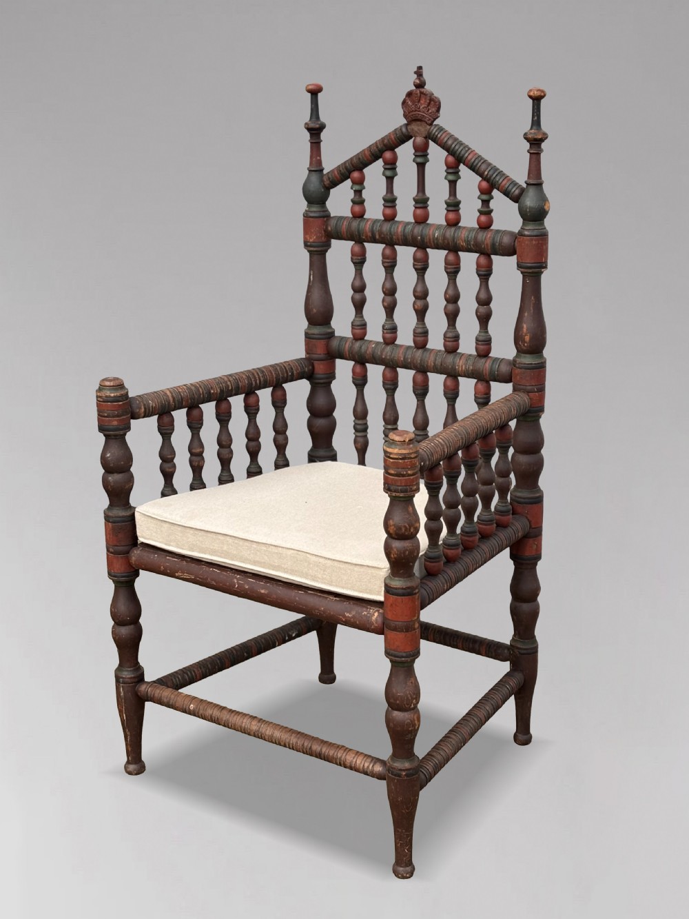 A 19th-century Swedish country throne armchair constructed with polychrome turned bobbins, a carved crown top finial, and a light cushion. View XI