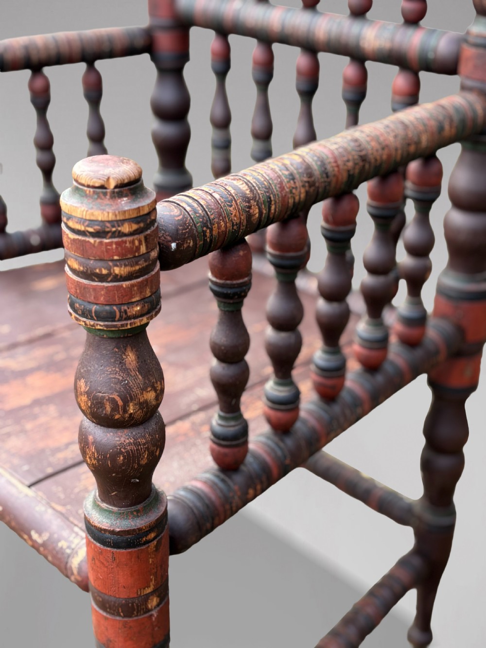 A 19th-century Swedish country throne armchair constructed with polychrome turned bobbins, a carved crown top finial, and a light cushion. View XII