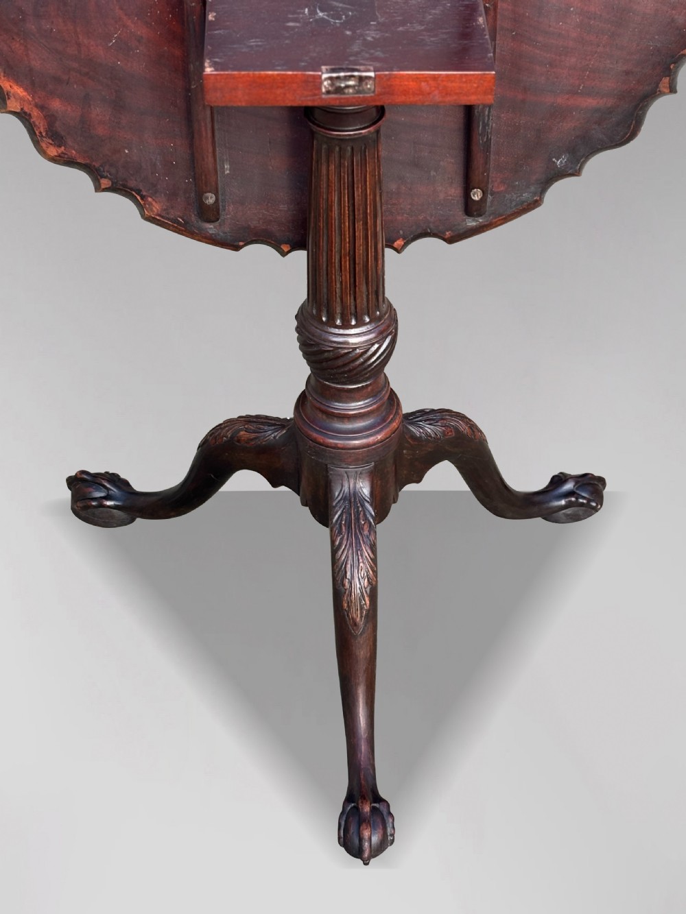 An 18th-century George III mahogany tilt-top tripod table featuring a carved piecrust rim, a fluted column, and cabriole legs ending in claw and ball feet. View V