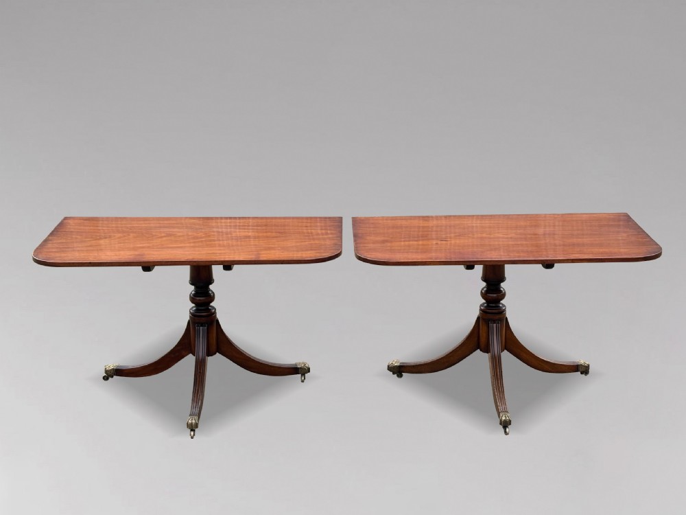 An early nineteenth-century mahogany twin pedestal dining table with a rounded rectangular top, reeded splayed legs, and brass castors. View IV