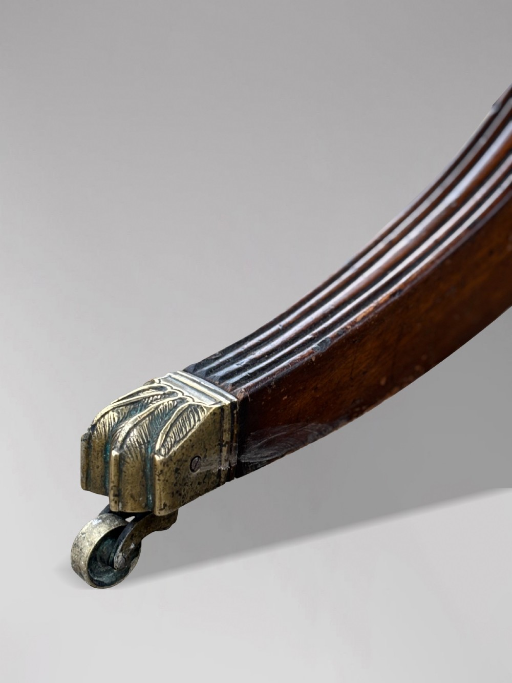An early nineteenth-century mahogany twin pedestal dining table with a rounded rectangular top, reeded splayed legs, and brass castors. View VIII