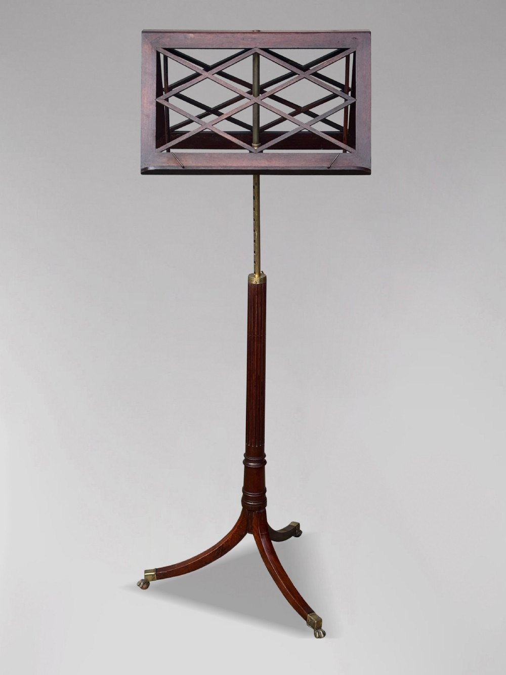 A 19th-century Regency mahogany duet music stand featuring a double-sided lattice desk, adjustable brass column, fluted stem, and tripod base with brass castors. View II