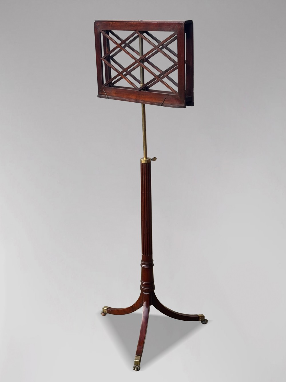 A 19th-century Regency mahogany duet music stand featuring a double-sided lattice desk, adjustable brass column, fluted stem, and tripod base with brass castors. View III