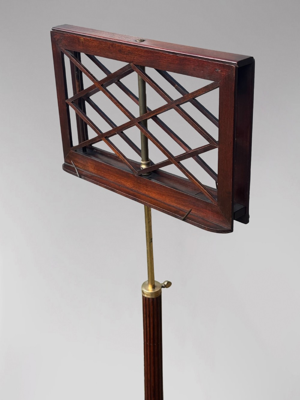 A 19th-century Regency mahogany duet music stand featuring a double-sided lattice desk, adjustable brass column, fluted stem, and tripod base with brass castors. View VI