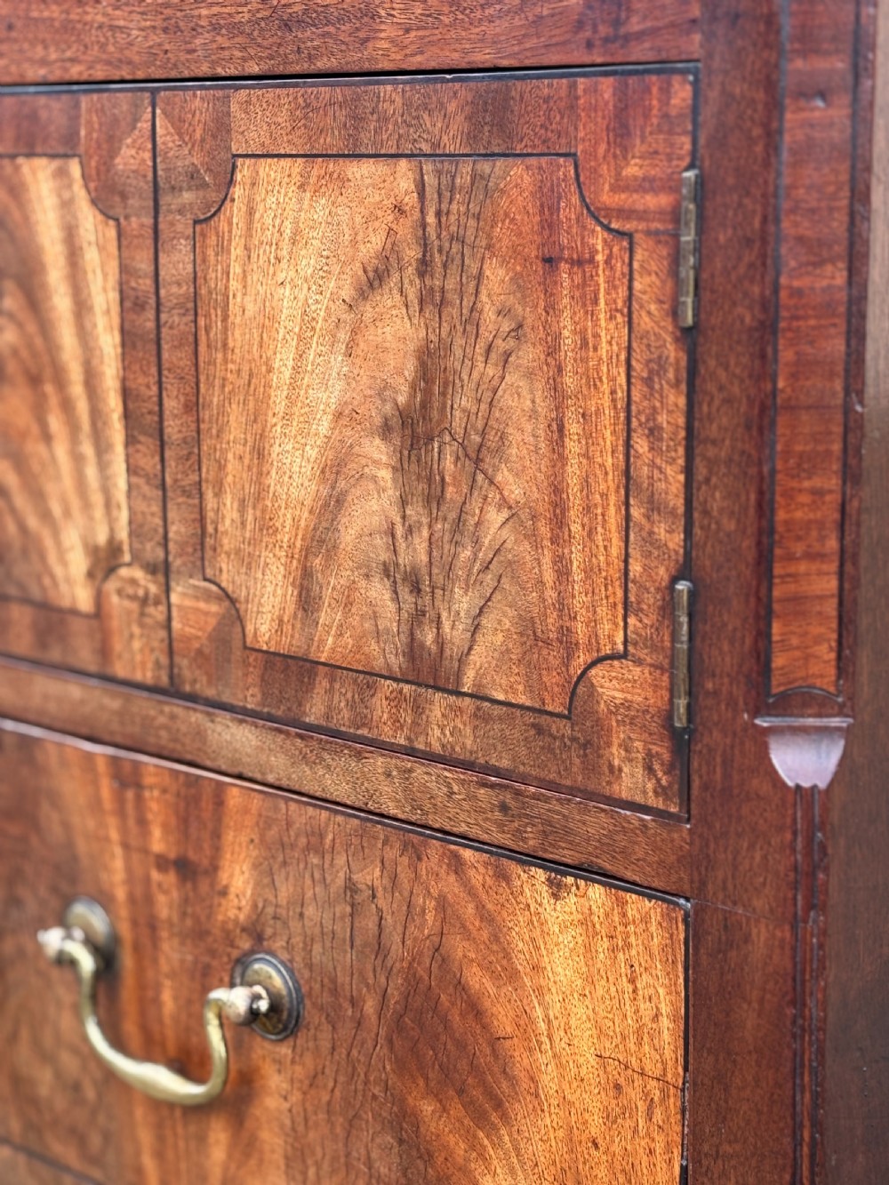 An 18th-century George III mahogany tray-top commode featuring shaped gallery sides, a cupboard with twin panel doors, a lower drawer with brass swan-neck handle, and square legs. View V