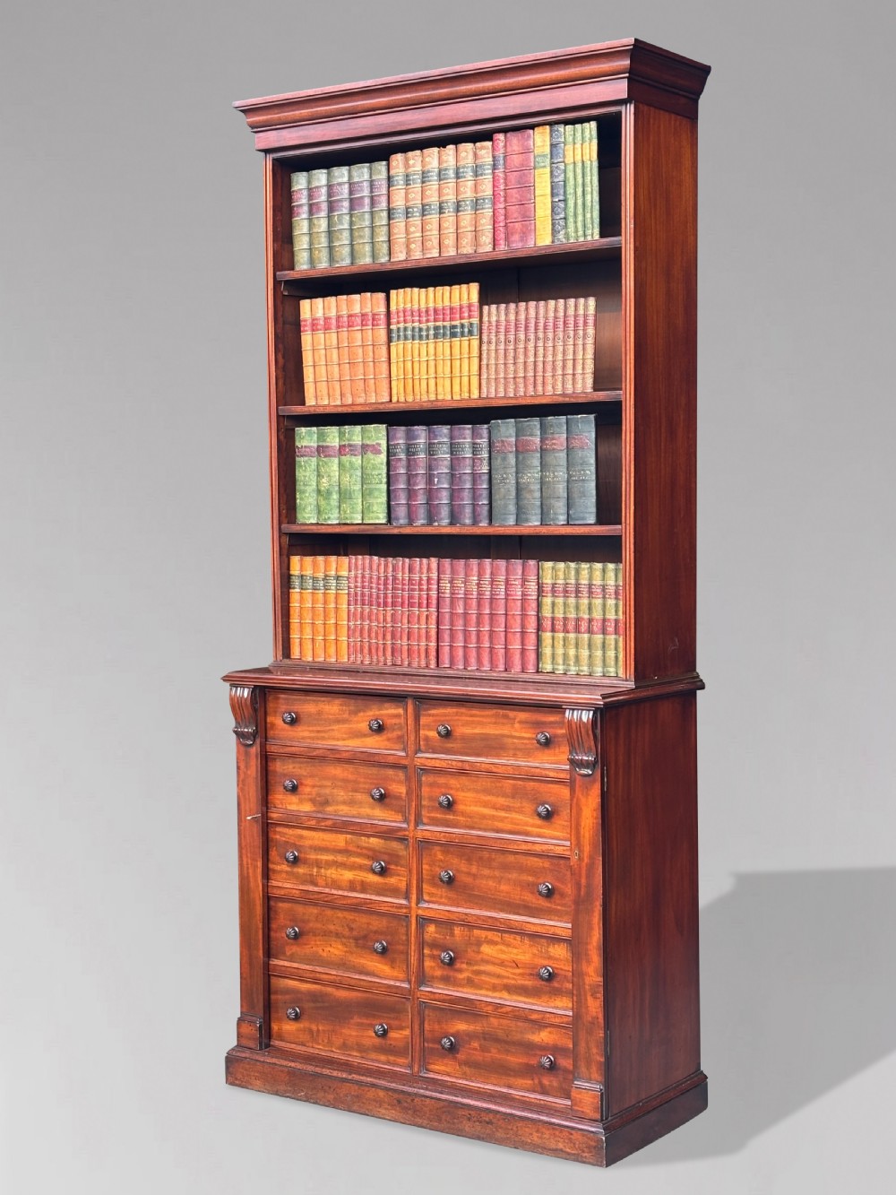 A nineteenth-century mahogany open library bookcase featuring a Wellington chest base with ten small drawers and open adjustable upper shelves.
