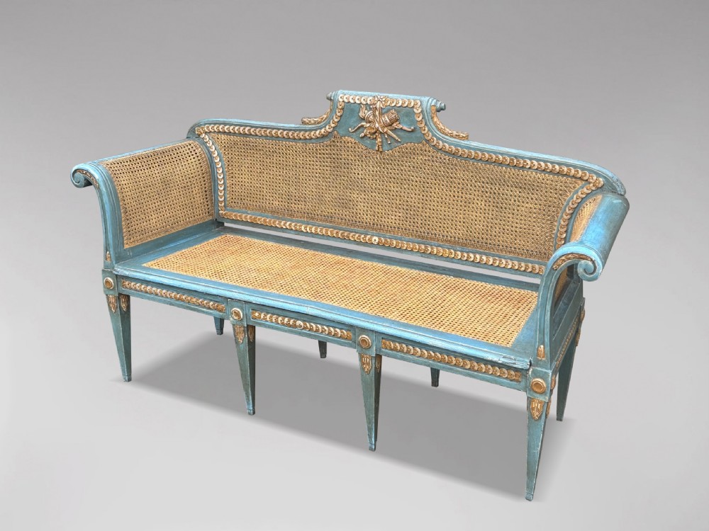A late 19th-century Louis XVI style settee featuring blue painted trim with gold leaf details, woven cane seat and back panels, and six fluted legs. View III