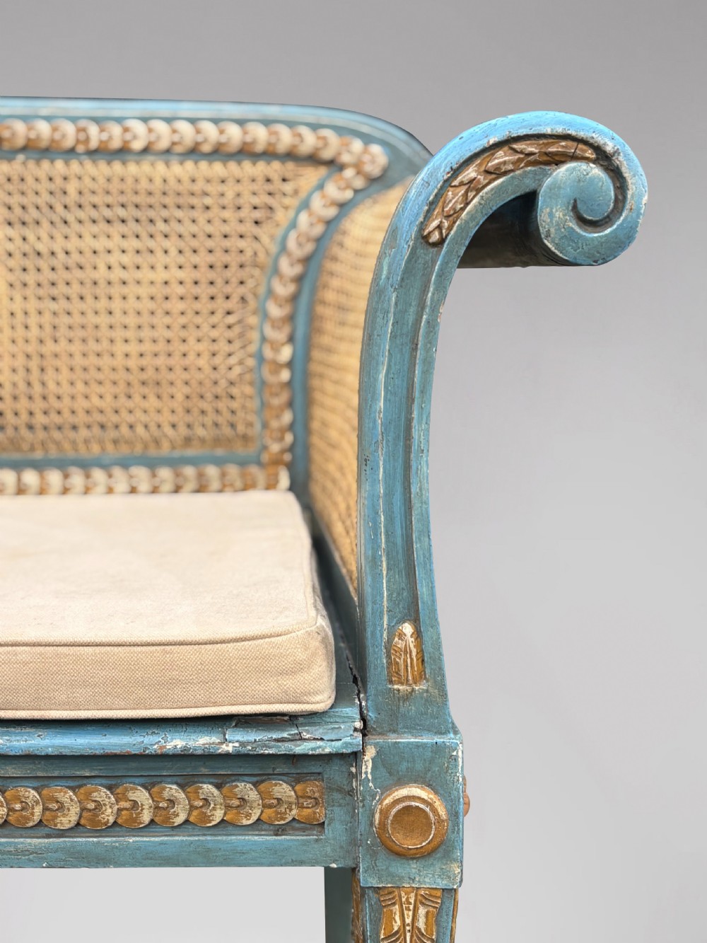 A late 19th-century Louis XVI style settee featuring blue painted trim with gold leaf details, woven cane seat and back panels, and six fluted legs. View VIII