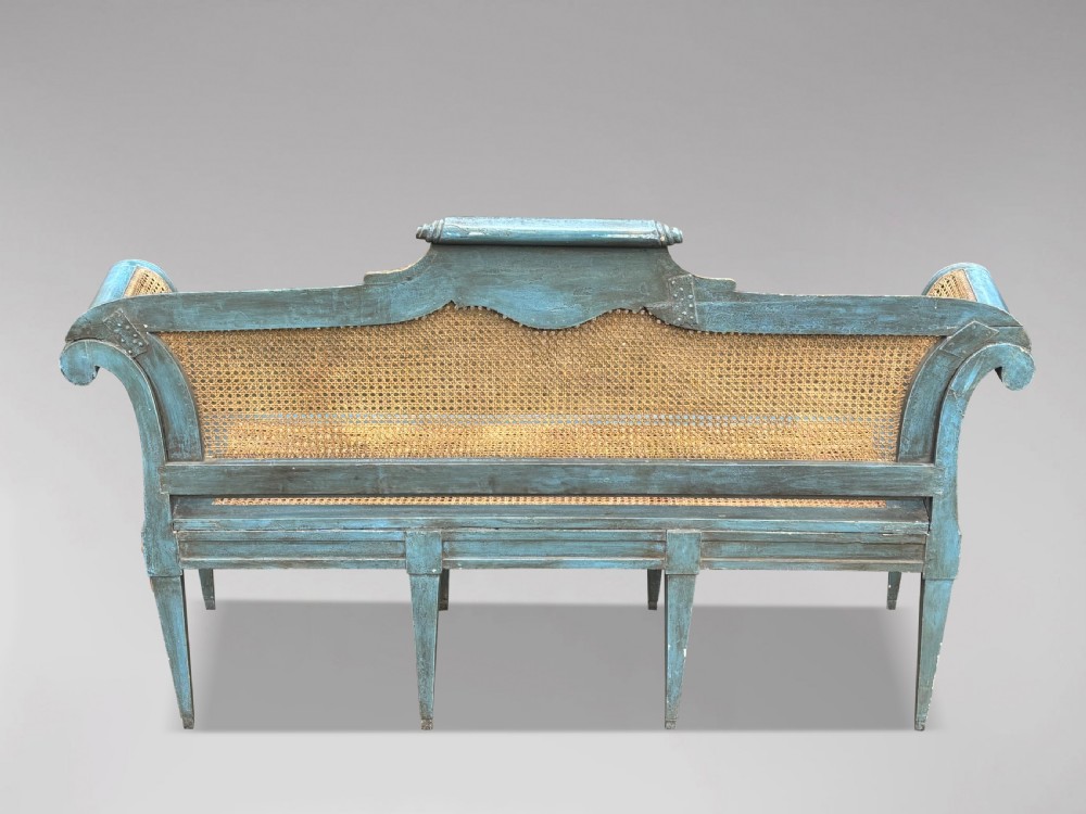 A late 19th-century Louis XVI style settee featuring blue painted trim with gold leaf details, woven cane seat and back panels, and six fluted legs. View IX